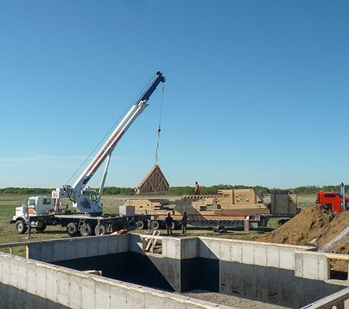 a crane unloading building material from truck